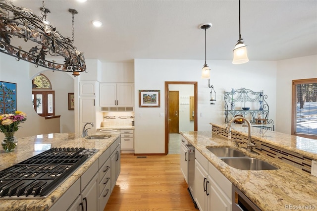 kitchen with decorative light fixtures, black gas stovetop, sink, and white cabinets