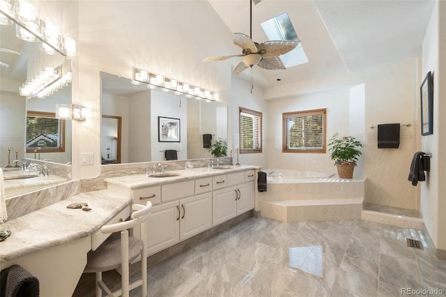 bathroom featuring a relaxing tiled tub, a healthy amount of sunlight, vanity, and vaulted ceiling with skylight