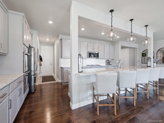 14565 Vancouver Pl, Parker, CO 80134 - kitchen with stainless steel appliances, recessed lighting, dark wood-style floors, a kitchen bar, and light stone counters