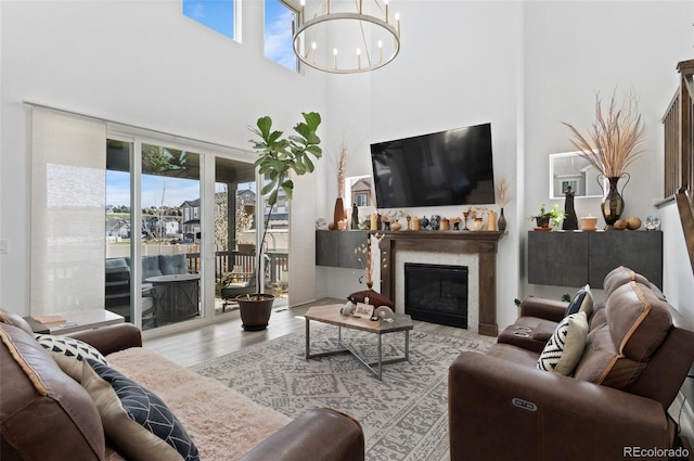 6454 Leathers Ln, Parker, CO 80134 - living room featuring a towering ceiling, a chandelier, a glass covered fireplace, and wood finished floors