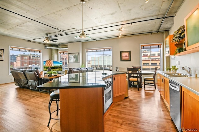 kitchen featuring a kitchen island, decorative light fixtures, sink, stainless steel appliances, and light hardwood / wood-style flooring