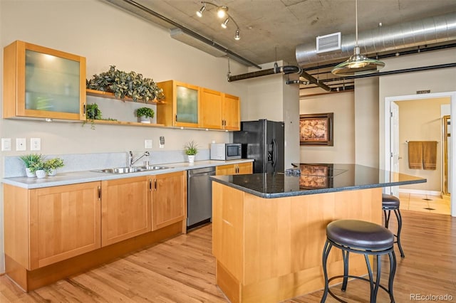 kitchen with a breakfast bar, sink, light wood-type flooring, a kitchen island, and stainless steel appliances