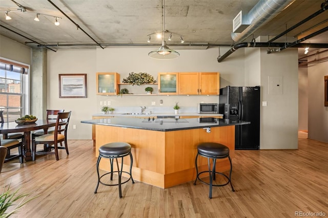 kitchen featuring sink, black fridge, a center island, light hardwood / wood-style flooring, and a kitchen breakfast bar