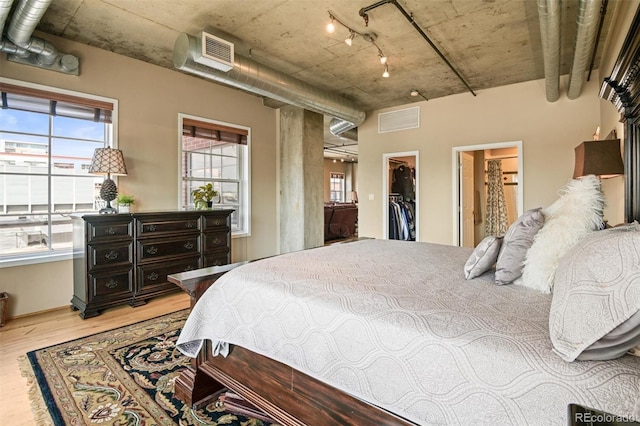 bedroom with ensuite bathroom, a spacious closet, a closet, and light hardwood / wood-style flooring