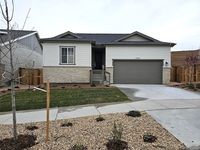 view of front of house featuring stone siding, driveway, and a garage