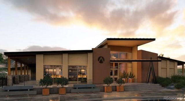 back of property at dusk featuring stucco siding