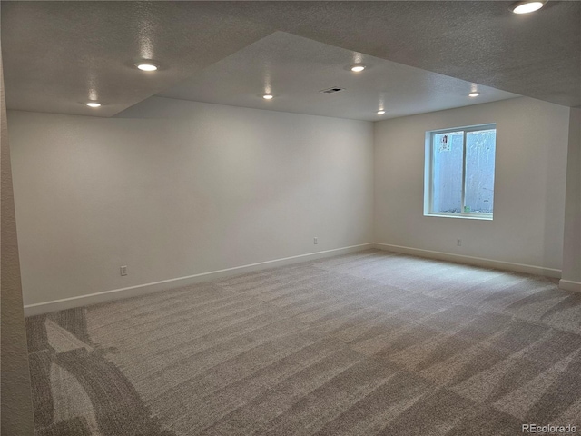 carpeted spare room featuring a textured ceiling, baseboards, and recessed lighting
