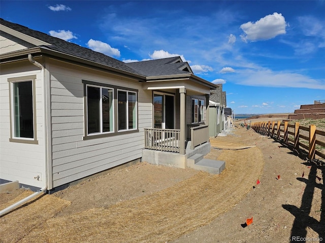 view of property exterior with fence and roof with shingles