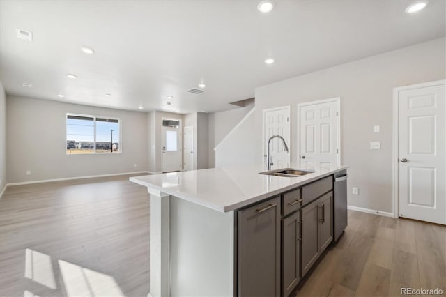 kitchen with light hardwood / wood-style flooring, sink, an island with sink, and dishwasher