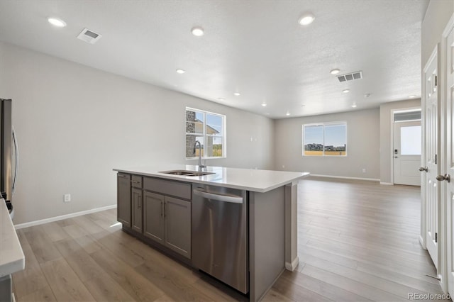 kitchen featuring light wood-type flooring, appliances with stainless steel finishes, plenty of natural light, and a center island with sink