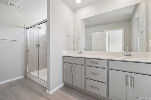 bathroom with vanity, hardwood / wood-style flooring, and a shower with door