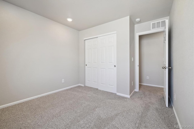 unfurnished bedroom featuring light carpet and a closet