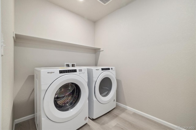 clothes washing area with light hardwood / wood-style flooring and washing machine and dryer