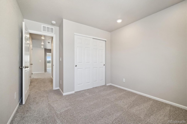 unfurnished bedroom featuring a closet and light colored carpet