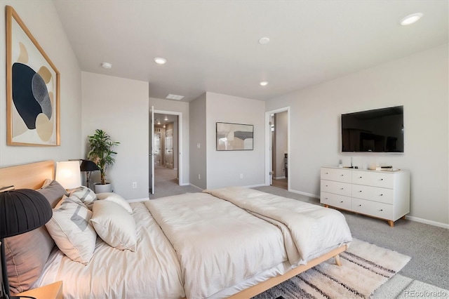 bedroom with ensuite bathroom and light carpet