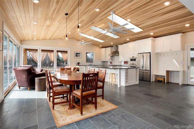 dining area with wood ceiling, a healthy amount of sunlight, ceiling fan, and dark tile floors