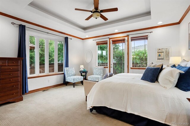 bedroom featuring multiple windows, ceiling fan, a tray ceiling, and light carpet