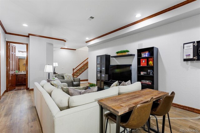 living room with light wood-type flooring and ornamental molding