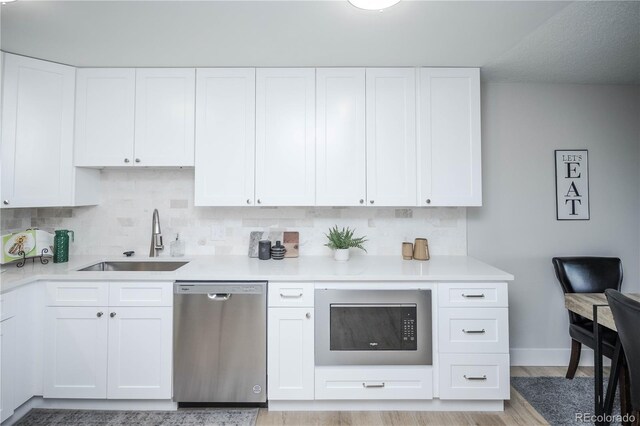 9155 E Center Ave Unit 4B, Denver, CO 80247 - kitchen with appliances with stainless steel finishes, decorative backsplash, white cabinets, and light countertops