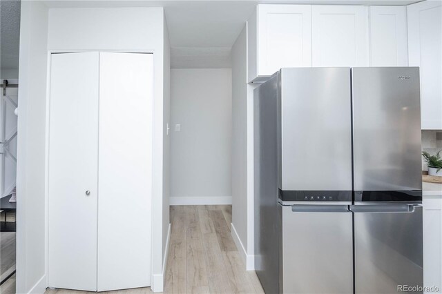 9155 E Center Ave Unit 4B, Denver, CO 80247 - kitchen featuring freestanding refrigerator, light wood-type flooring, white cabinets, light countertops, and a barn door