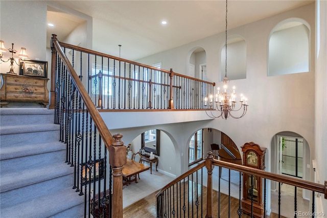 staircase featuring an inviting chandelier, carpet, and a high ceiling