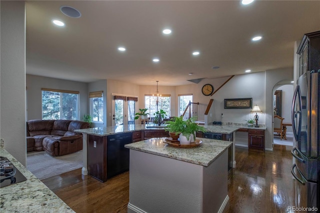 kitchen with dark brown cabinets, hanging light fixtures, a kitchen island, and black appliances