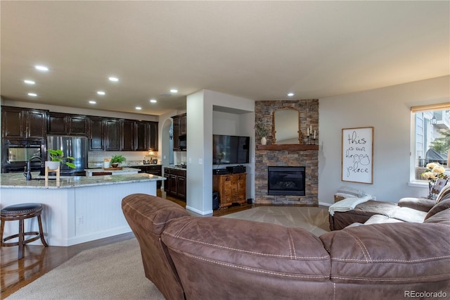 living room featuring a stone fireplace and sink