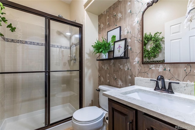 bathroom featuring vanity, a shower with shower door, and toilet