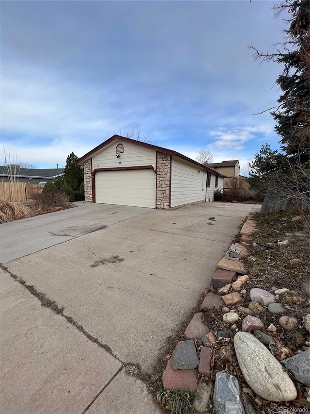 view of side of home featuring a garage, stone siding, and an outdoor structure