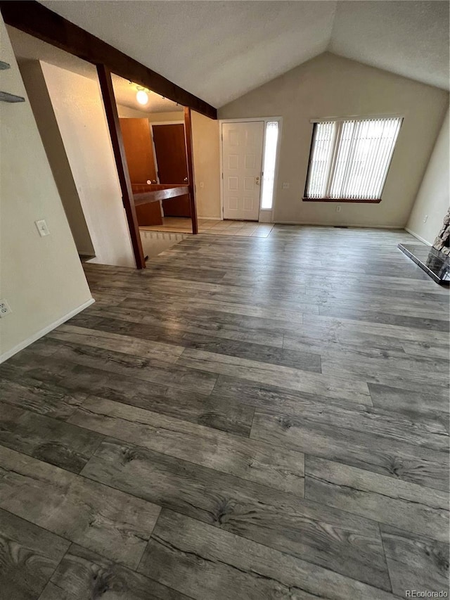 unfurnished living room with lofted ceiling, wood finished floors, and baseboards