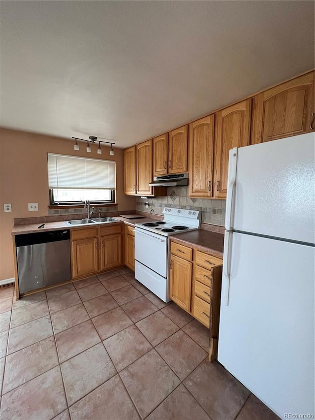 kitchen featuring light tile patterned floors, tasteful backsplash, a sink, white appliances, and under cabinet range hood