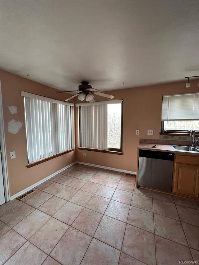 kitchen with light tile patterned floors, visible vents, stainless steel dishwasher, a sink, and baseboards