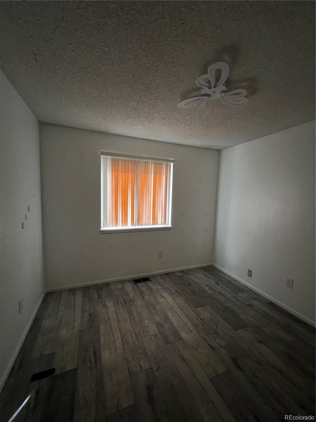 spare room featuring a textured ceiling, ceiling fan, wood finished floors, and baseboards