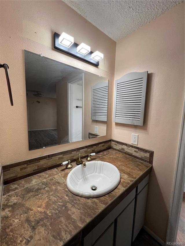 bathroom featuring a textured wall, a textured ceiling, and vanity