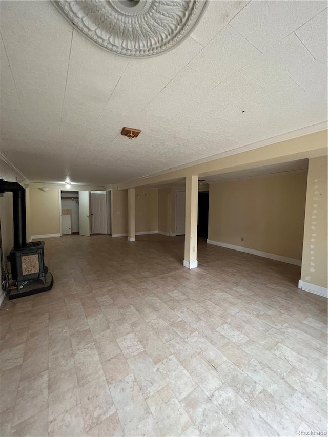 finished below grade area with ornamental molding, a wood stove, and baseboards