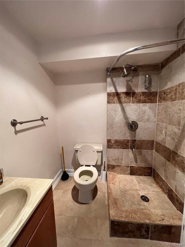 full bathroom with a tile shower, vanity, and toilet