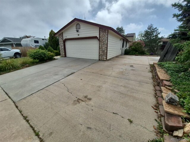 2758 S Salida St, Aurora, CO 80013 - view of side of home featuring concrete driveway, a garage, and stone siding