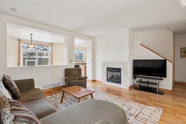 living area with visible vents, baseboards, wood finished floors, and a fireplace