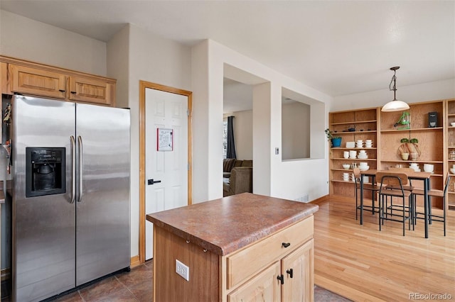 kitchen with visible vents, a kitchen island, stainless steel refrigerator with ice dispenser, wood finished floors, and dark countertops