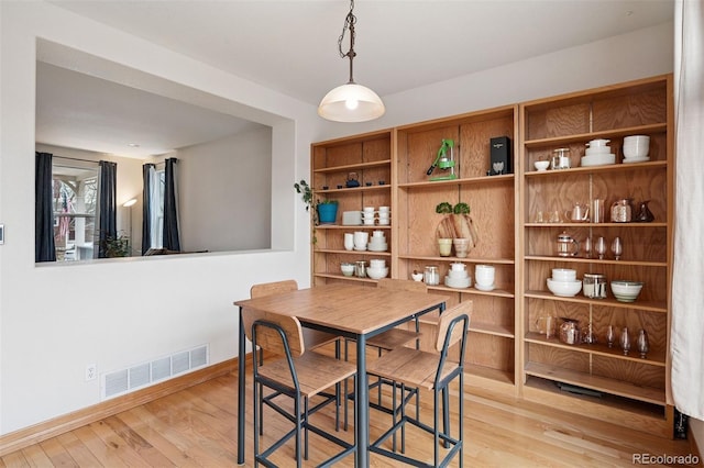 dining area with wood finished floors, baseboards, and visible vents