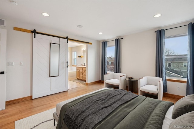 bedroom with light wood-type flooring, a barn door, and recessed lighting