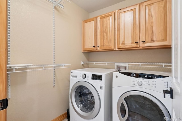 clothes washing area featuring cabinet space and washer and clothes dryer