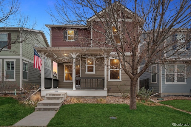 traditional home featuring covered porch and a front yard