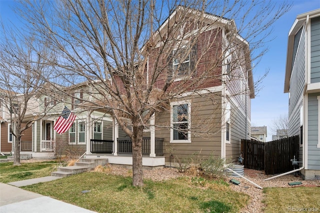 view of front of home with a porch, fence, and a front lawn