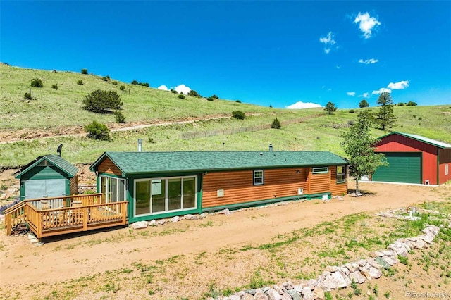 rear view of house with a rural view, an outdoor structure, a wooden deck, and a garage