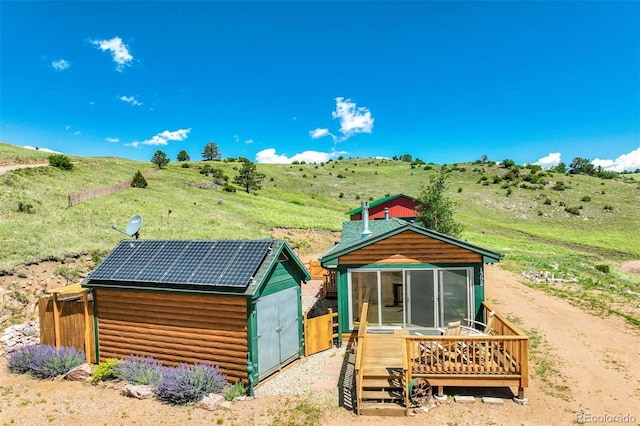 rear view of property featuring a rural view, a deck, and solar panels