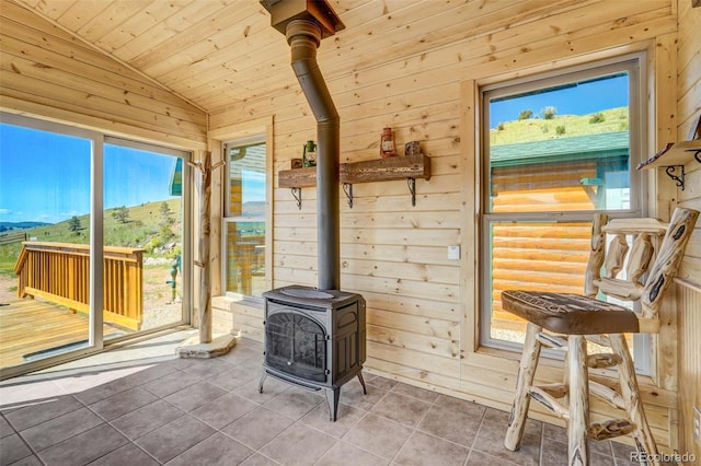 interior space with a mountain view, a wood stove, lofted ceiling, and wood ceiling