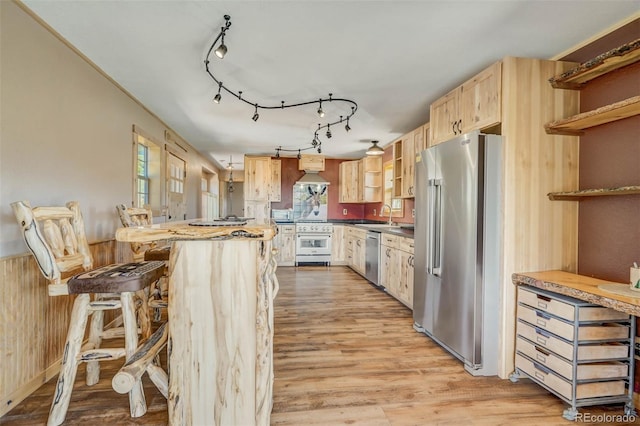 kitchen featuring wood walls, a kitchen breakfast bar, high quality appliances, light hardwood / wood-style flooring, and sink