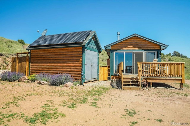 rear view of house featuring a deck and solar panels