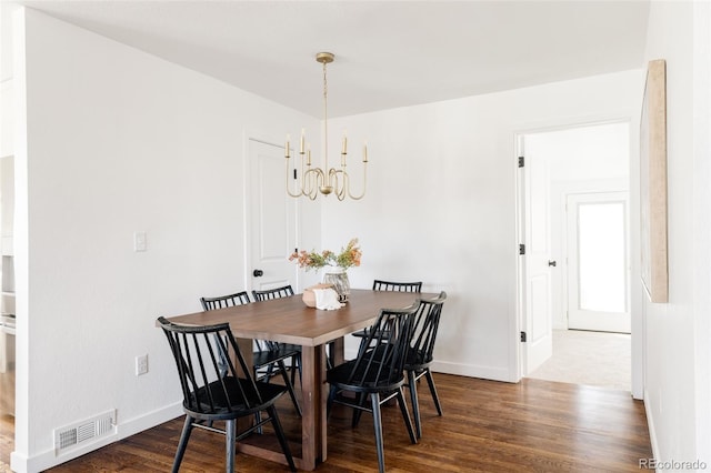 dining space with dark hardwood / wood-style floors and a chandelier